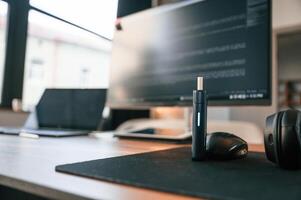 Close up view of electronic cigarette, mouse for computer, laptop and monitor with programming language code on it photo