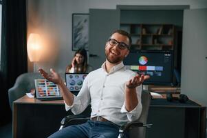 Positive, man is smiling. Two employees are working together in the modern office photo