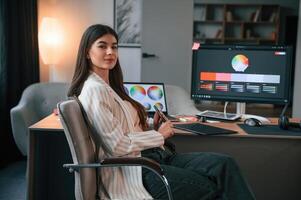 Sitting on the chair.. Designer's software on the screen. Woman is working in the modern office with computer photo