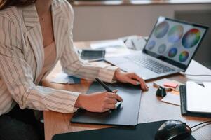Drawing by ,using graphic tablet. Woman is working in the modern office with computer photo