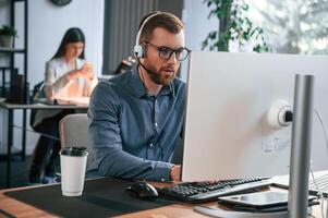 Man is using computer.. Two employees are working together in the modern office photo