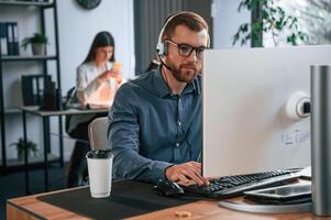 Man ,is using computer. Two employees are working together in the modern office photo