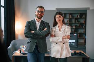 Standing with ,arms crossed.. Two employees are working together in the modern office photo