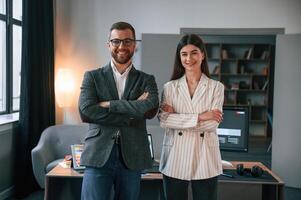 Standing with, arms crossed. Two employees are working together in the modern office photo
