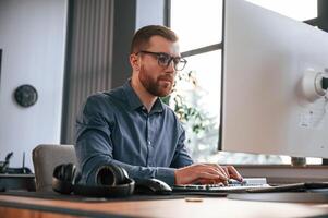 Typing on the keyboard. Man in formal clothes is working in the modern office. Using computer photo