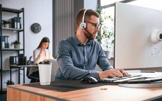 Man i,s using computer. Two employees are working together in the modern office photo