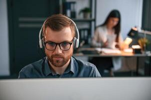 Portrait, of man. Woman is on background. Two employees are working together in the modern office photo