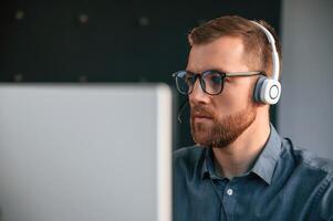 Portrait of man that is in formal clothes, working in the modern office. Using computer photo