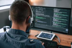 Software ,developer is writing code.. Man in formal clothes is working in the modern office. Using computer photo