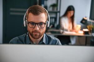 Portrait of man. Woman is ,on background. Two employees are working together in the modern office photo