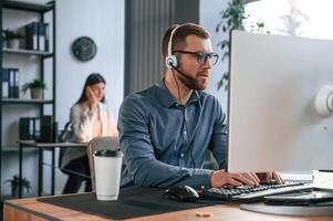 Man is using computer. Two employees are working together in the modern office photo
