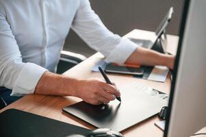With, graphic tablet.. Close up view of designer's hands. Man in formal clothes is working in the modern office. Using computer photo
