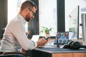 Man ,in formal ,clothes is working in the modern office. Using computer photo