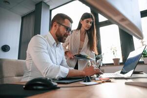 Side view. Paper work. Two employees are ,together in the modern office photo