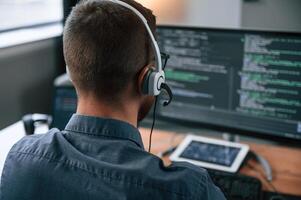 Software, developer is writing code. Man ,in formal clothes is working in the modern office. Using computer photo
