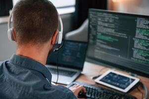 Software developer is,writing code. Man in formal clothes is working in the modern office. Using computer photo