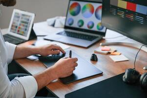 With graphic tablet. Close up view of designer's hands. Man in formal clothes is working in the modern office. Using computer photo