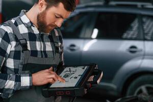 Graphic, information is on the tablet. Man in uniform is working in the auto salon photo