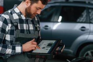 Graphic,, information is on the tablet. Man in uniform is working in the auto salon photo
