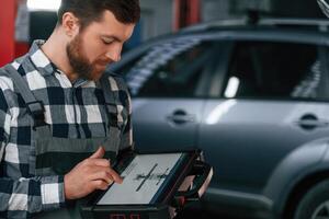 Graphic information is on the, tablet. Man in uniform is working in the auto salon photo