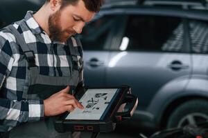 Graphic ,information, is on the tablet. Man in uniform is working in the auto salon photo