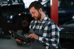Holding tablet.. Man ,in uniform is working in the auto salon photo