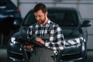 Holding tablet... Man in uniform is working in the auto salon photo