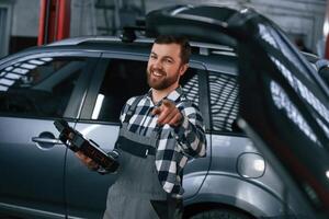 With ,tablet in hands. Man in uniform is working in the auto salon photo