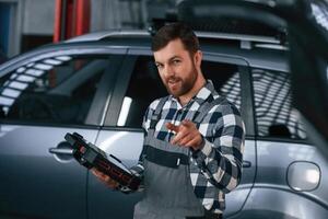 Holding tablet.. Man in uniform is working in the auto salon photo