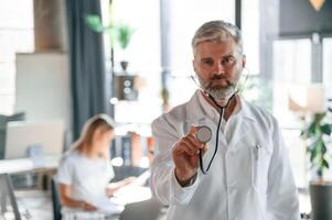 Man is ,standing in front of woman. Two clinic workers are indoors together photo