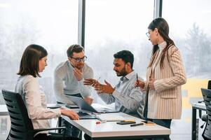 Having ,the ,meeting. Four people are working in the office together photo