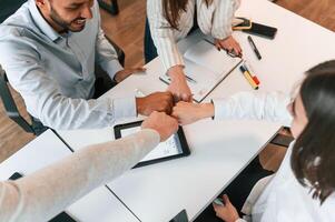 Success, making hand gestures. Four ,people are working in the office together photo