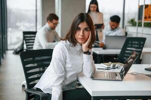 Gorgeous woman is in the front of her,colleagues. Four people are working in the office together photo