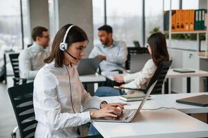 Woman is working by laptop.. Four, people are working in the office together photo