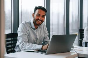 Beautiful indian man ,is working in the office by laptop photo