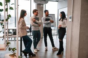 Four, people standing in the office and working together photo