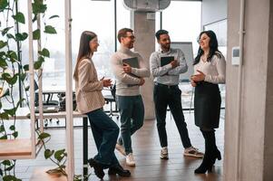 Four people ,standing ,in the office and working together photo