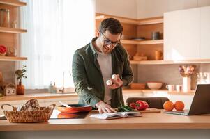 Holding two eggs in hand. Handsome man is on the kitchen at daytime photo