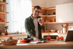 Holding, two eggs in hand. Handsome man is on the kitchen at daytime photo