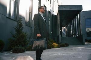 Stylish formal clothes. Handsome man is outdoor near the business building photo