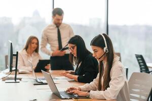 Sitting, by ,the table. Business people in formal clothes are working in the office together photo