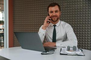 Handsome man ,in formal clothes is working by laptop in the office photo