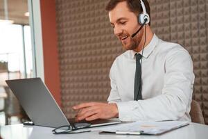 Using laptop. Handsome, man in formal clothes is in the office photo