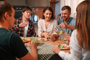 Delicious food. Group of people are on ,the kitchen, having dinner, spending time together photo