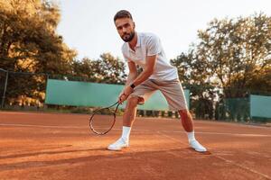 Active training.. Young man is on the tennis court at sunny daytime photo