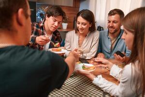 Delicious food. Group of ,people are on the kitchen, having dinner, spending time together photo