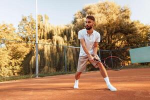 Active training. Young, man is on the tennis court at sunny daytime photo