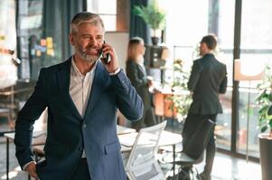 Man, is standing ,and having phone call. Group of business people are working in the modern office photo