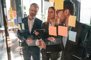 Bunch of, the stickers are on the glass. Group of business people are working in the modern office photo