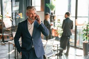 Man is standing and having phone call.. Group of business people are working in the modern office photo